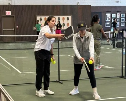A Velto coach guiding a first-time player at the net